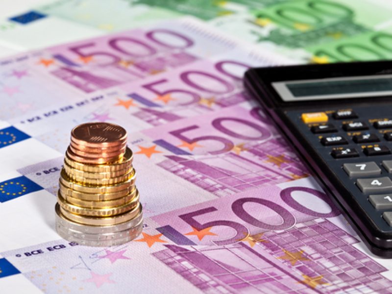 Euro banknotes, pile of coins and calculator - closeup shot