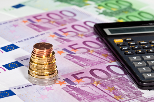Euro banknotes, pile of coins and calculator - closeup shot